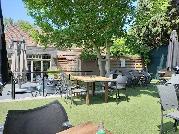 Het groene terras van St Anneke met tafels en stoelen onder de bomen