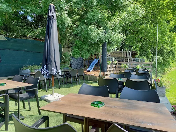 Tafels op het groene terras met een glijbaan op de achtergrond