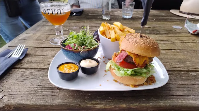 Burger met frietjes, salade en sausjes op een terrastafel